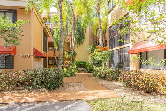 Front view of a multi-story building with trees and bushes in front.