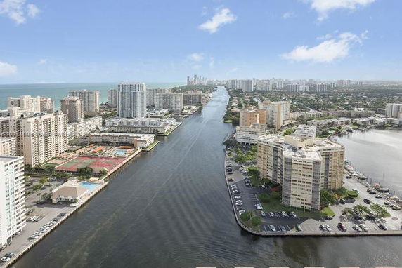 Aerial view of a cityscape with multiple high-rise buildings along a waterway.