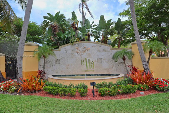 Entrance sign of a condominium complex with lush tropical landscaping.
