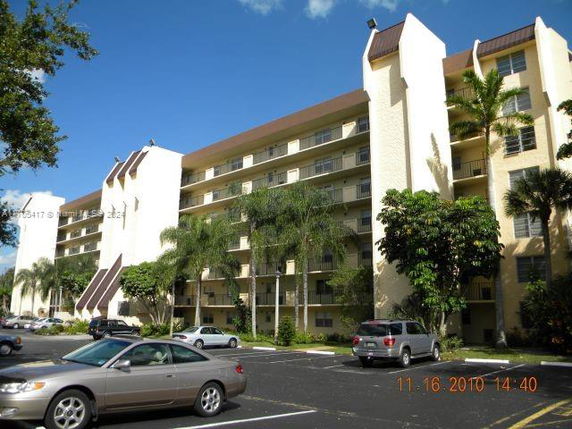 Front view of a multi-story residential building with parking area.