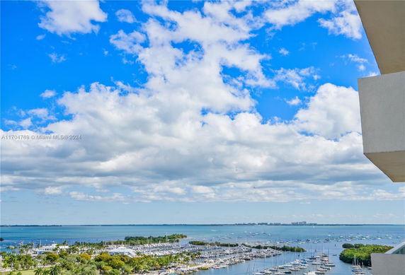 View of a marina with boats and a distant horizon over the water, seen from a high vantage point.