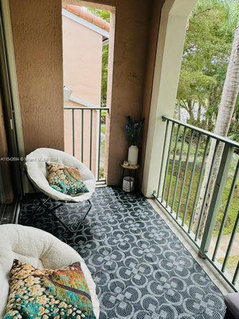 Balcony with chairs overlooking trees and a distant lake.