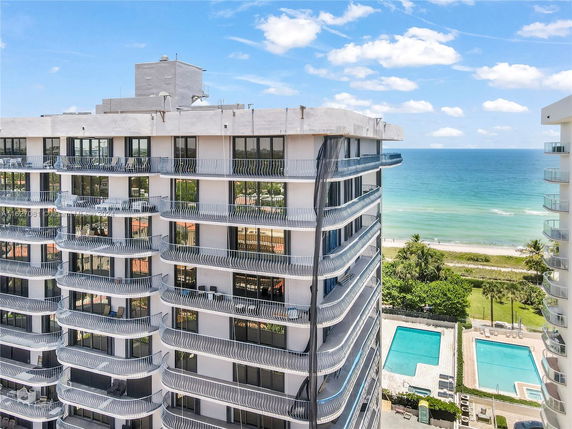 Front view of a high-rise building with curved balconies near the ocean.