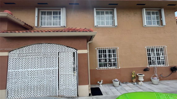 Front view of a two-story house with barred windows and a decorative white metal gate.