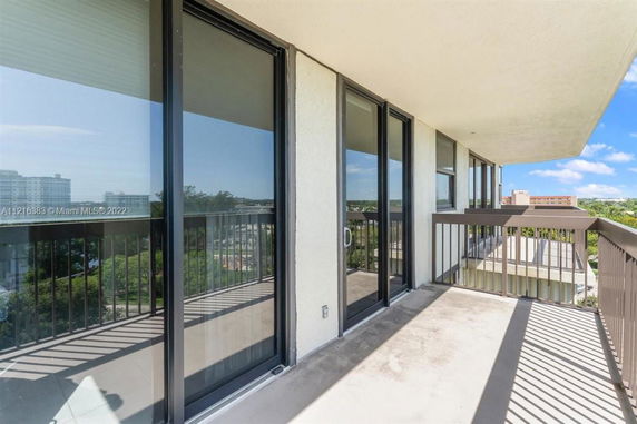 Balcony with glass doors and railings offering panoramic view of the city.