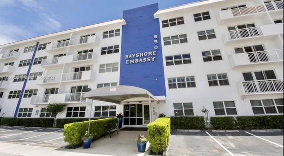 Front view of a multi-story building with a blue central section and balconies.