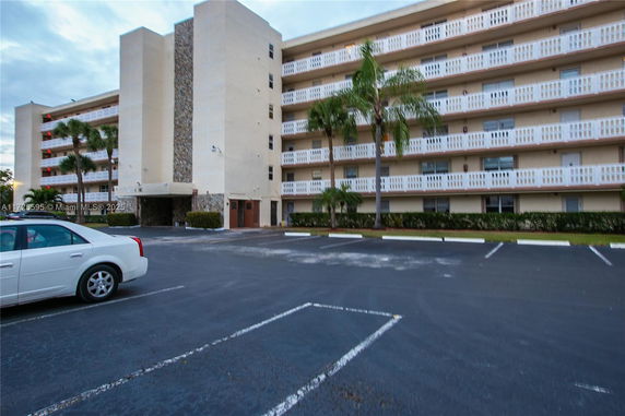 Exterior view of a multi-story building with parking spaces in front.