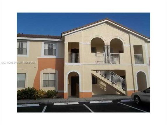 Front view of a two-story building with arches and outdoor staircases.