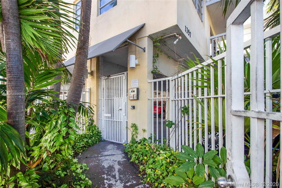 Entrance view of a building with a gated entry and surrounding greenery.