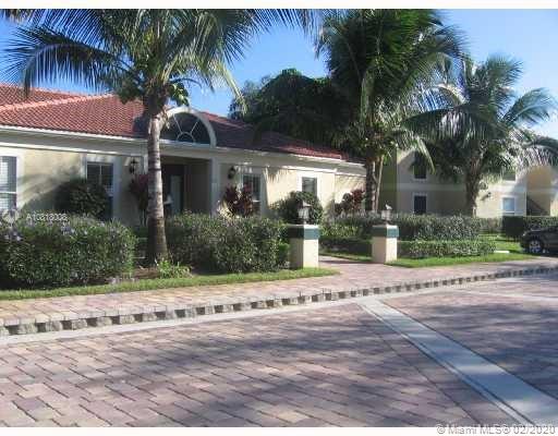 Front view of a single-story house with a red-tiled roof and palm trees.