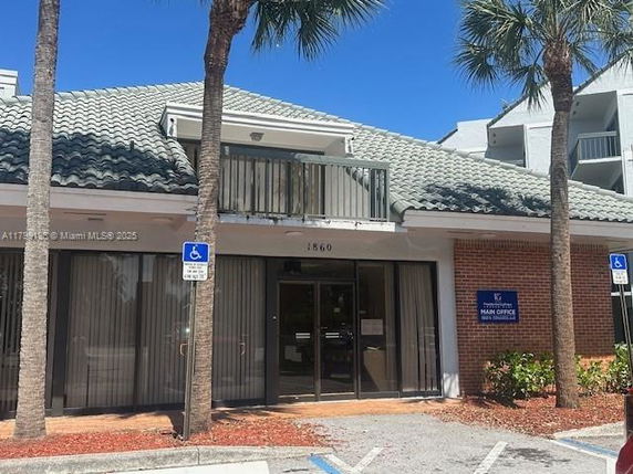 Front view of a building with a tile roof and a balcony over the entrance.
