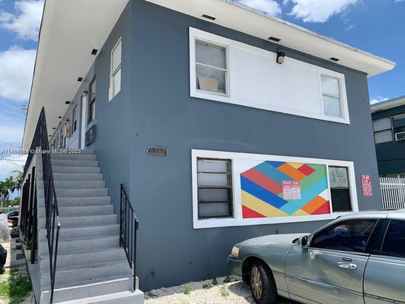 Front view of a two-story building with external staircase and colorful mural on the wall.