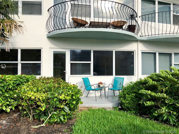 Front view of a multi-story building with a balcony and patio area.