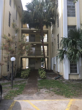 Front view of a multi-story building with balconies and a walkway.