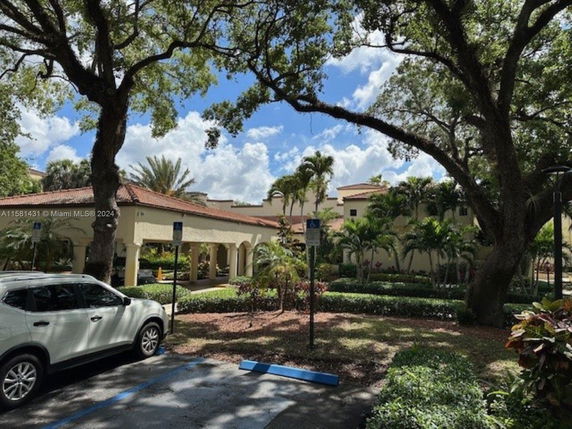 Outdoor parking area in front of a building with trees and landscaping.