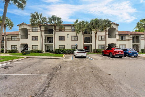 Outdoor parking area in front of a three-story residential building with balconies.