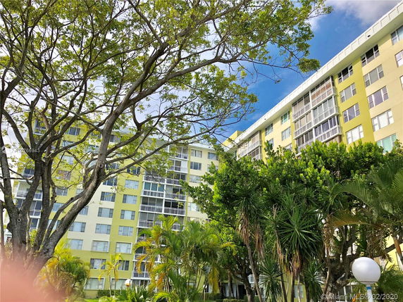 View of a multi-story residential building surrounded by trees and greenery.