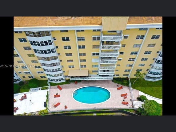 Aerial view of a residential building with an oval swimming pool and surrounding patio area.