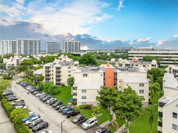 Aerial view of apartment buildings with multiple floors and a parking area.