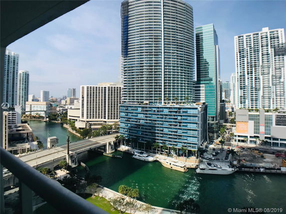 Panoramic view of high-rise buildings and a riverfront in an urban area.