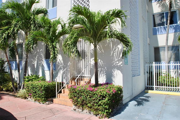 Front view of a multi-story building with exterior stairs and palm trees.