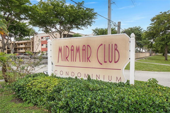 Front view of a condominium building with a sign reading 'Miramar Club'.