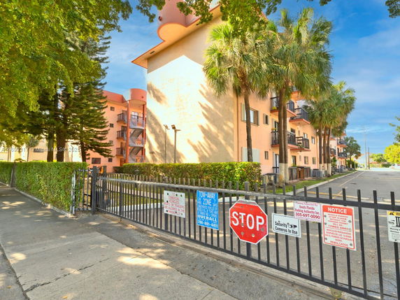 Front view of a multi-story apartment building with balconies and a gated entrance.