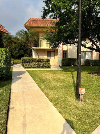 Front view of a two-story house with a balcony and red roof tiles.