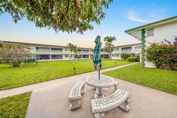 View of courtyard between two-story buildings with balconies and a central grassy area.