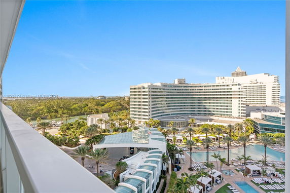 Panoramic view of a large modern hotel building with a pool area and landscaped surroundings.
