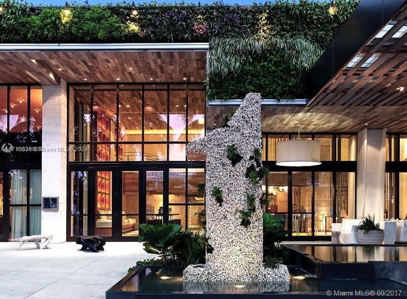 Front view of a modern building with large glass windows and green wall decorations.