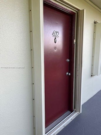 Front view of a red door with the number 402 on a building exterior.