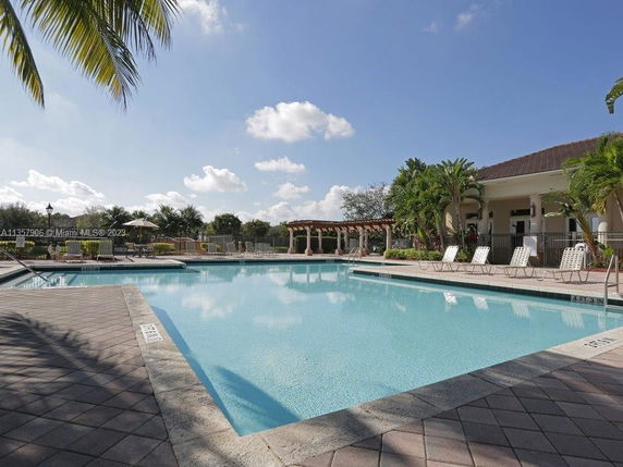 Outdoor swimming pool with lounge chairs and palm trees.