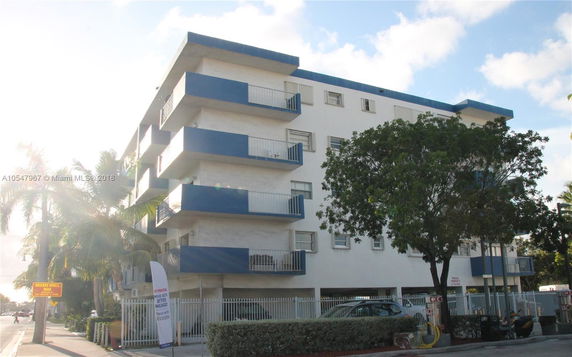 Front view of a multi-story building with balconies and a blue and white color scheme.