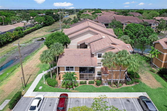 Aerial view of multiple residential buildings with tiled roofs surrounded by trees and green areas.