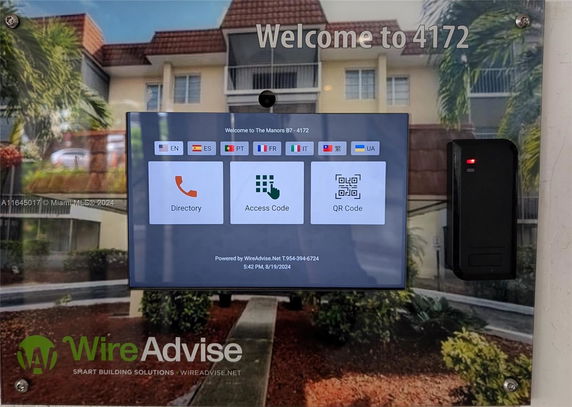 Front view of a multi-story residential building with entrance directory screen.