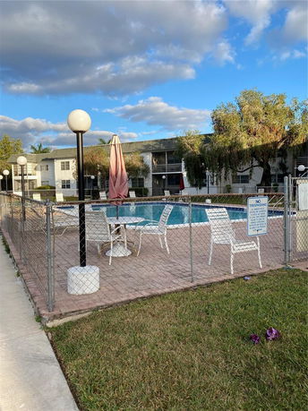 Outdoor swimming pool area fenced with chairs and umbrellas nearby.