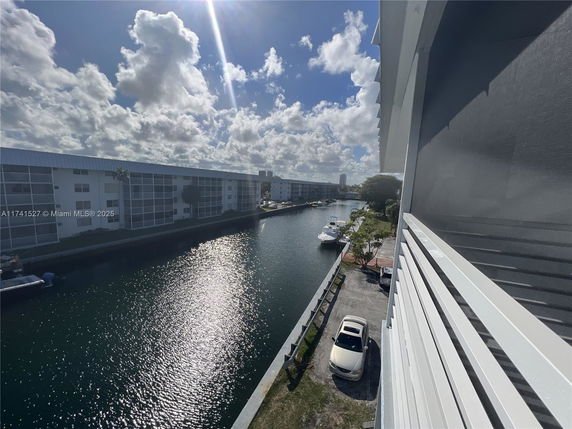 View from a building balcony overlooking a canal with parked boats and adjacent residential buildings.