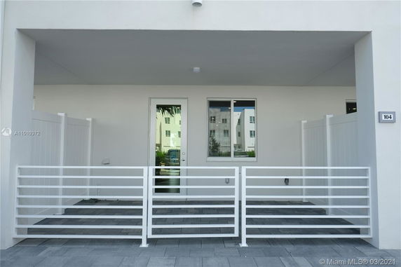 Front view of a building entrance with a metal railing and paved porch.