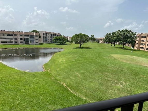 View of a green landscape with a pond and multi-story residential buildings.