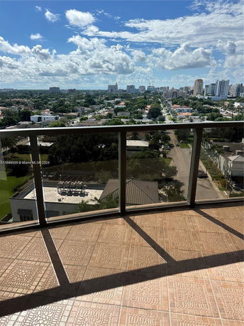 Panoramic view of cityscape from a balcony with glass railing.