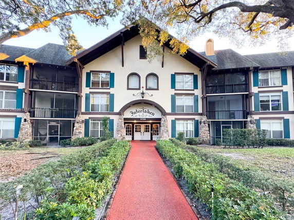 Front view of a multi-story building with balconies and an arched entrance.