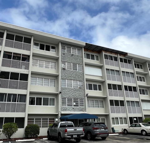 Front view of a multi-story apartment building with multiple windows and balconies.