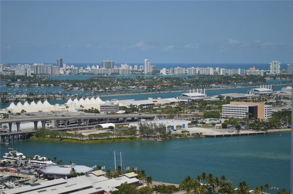 Aerial view of a coastal cityscape with numerous high-rise buildings and waterways.