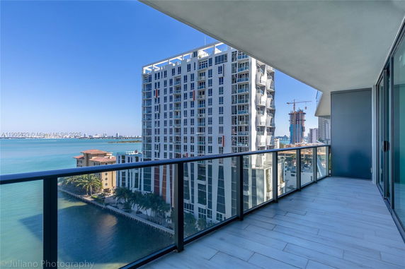 Panoramic view from a high-rise balcony overlooking a body of water and other buildings.