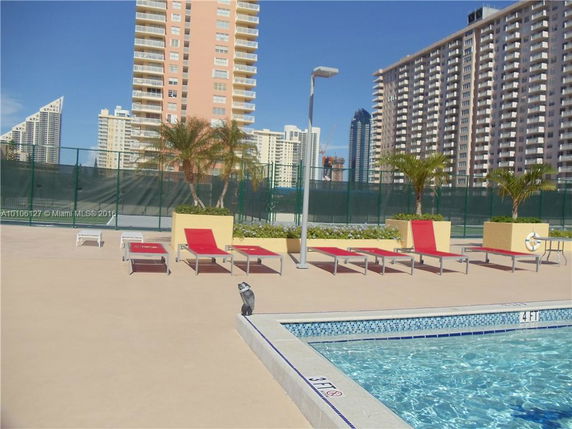 Poolside area with lounge chairs and surrounding high-rise buildings.