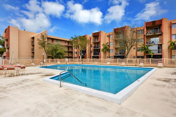 Outdoor area with a swimming pool in front of residential buildings.