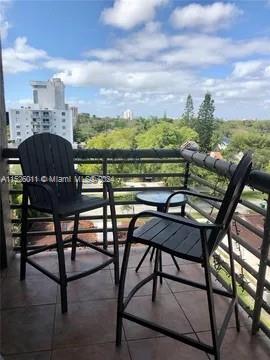 View from a balcony with two chairs overlooking buildings and trees.
