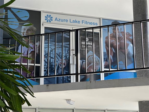 Front view of a fitness club with signage and promotional images on windows.