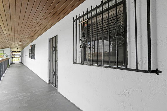 Exterior view of a corridor with metal-barred windows and doors.
